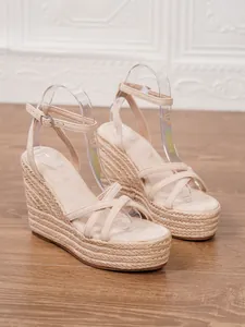 Close-up of stylish women's beige espadrille wedge sandals with braided rope platform.
