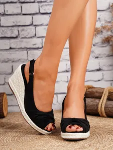 Primer plano de alpargatas de cuña negras con tira al tobillo y diseño de punta abierta