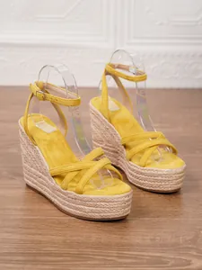 Macro view of yellow suede criss-cross straps on braided jute wedge platform sandals