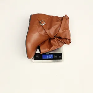 Detail showing a single brown slouchy mid-calf boot weighed on a digital scale at 312g.