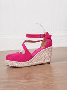 Gros plan latéral de sandales compensées espadrilles en daim fuchsia avec plateforme en jute