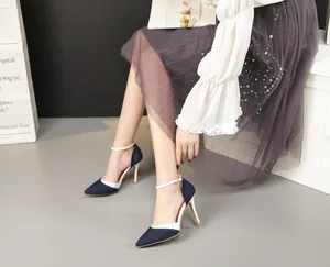 Close-up of denim pointed-toe high heels with white ankle straps and stiletto heels