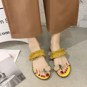 Detailed view of women's yellow flat flip-flop sandals featuring pearl pineapple and ruffles