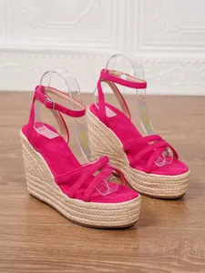 Side view of fuchsia suede espadrille wedge sandals with straw braided platform.