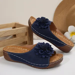Detailed view of navy blue wedge sandals featuring a large 3D flower decoration