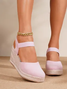 Primer plano de sandalias de cuña de ante rosa con plataforma de paja trenzada elegante
