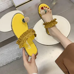 Close-up detail of stylish yellow flip-flop sandals featuring pearl pineapple ornament