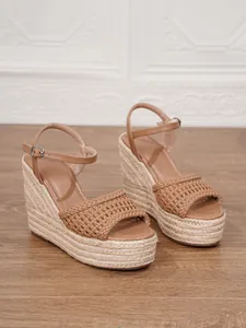 Detalle de sandalias de cuña espardeñas marrones con tira trenzada y hebilla