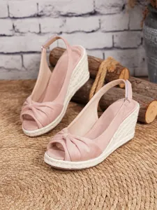 Primer plano de sandalias con cuña de ante rosa y suela de plataforma de cuerda de yute