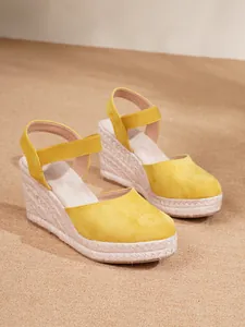 Detalle de sandalias de cuña de ante amarillo con suela de plataforma de cuerda trenzada