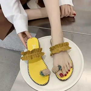 Detailed close-up of yellow flat sandals featuring pearl pineapple and ruffled strap
