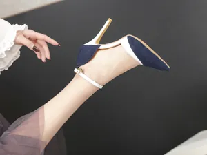 Elegant detail view of denim and white stiletto high heels with thin ankle strap