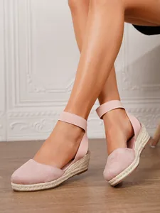 Primer plano de sandalias de cuña en gamuza rosa con correas elásticas al tobillo