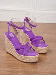 Close-up detail of purple suede wedge sandals featuring natural jute braided platform