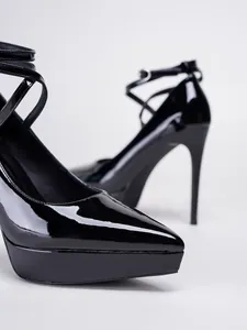 Detalle de zapatos de plataforma de charol negro con punta afilada y tacones de aguja