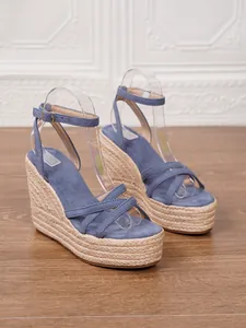 Close-up detail of blue suede wedge sandals featuring straw braided platform soles