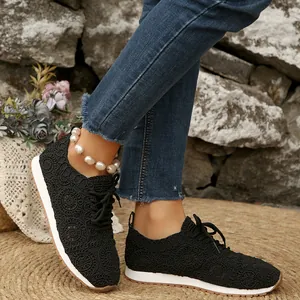 Close-up of black lace mesh sneakers with elegant floral patterns and white soles.