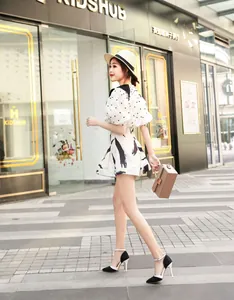 Side view of model wearing black and white pointed-toe stiletto pumps with ankle strap.