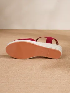 Detalle de sandalias de cuña de ante rojo con plataforma de yute y suela de talla 37.