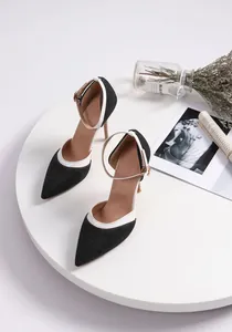 Detail shot of elegant black denim pointed-toe heels with white trim and ankle straps