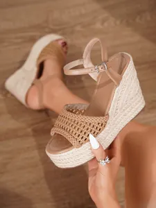 Detalle de sandalias con cuña beige con plataforma de esparto y cierre de hebilla al tobillo