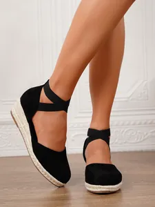Primer plano de sandalias de cuña tipo alpargata en ante negro con correas elásticas