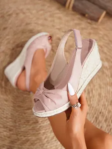 Primer plano de sandalias de cuña rosa con lazo y suela de esparto trenzado detalle