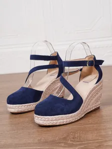 Détail de sandales compensées en daim bleu marine avec semelle en corde tressée