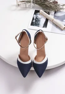 Top-down view of stylish denim pointed-toe pumps with elegant white trim and ankle straps