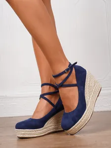 Primer plano de sandalias con cuña de ante azul con plataforma de esparto y correa al tobillo