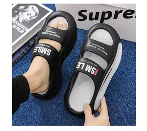 Detailed view of black EVA platform slippers with white text on a blue textured floor