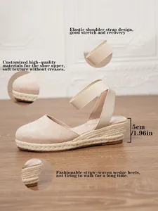 Detalle de sandalias de cuña tipo alpargata beige con tacón de 5 cm y correa de tobillo elástica.