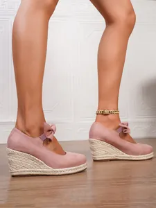 Cuñas de ante rosa estilo alpargata con detalle de lazo y suela de cuerda.