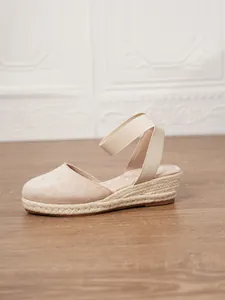 Detalle de sandalias de cuña beige con punta cerrada y suela de esparto trenzado