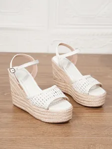 Detalle de la tira trenzada blanca y la plataforma de esparto en estas sandalias de cuña.