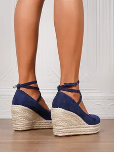 Vista de detalle de sandalias de cuña de ante azul con suelas de cáñamo trenzado.