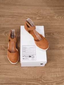 Sandalias de cuña tipo alpargata en ante marrón sobre caja de zapatos y suelo de madera