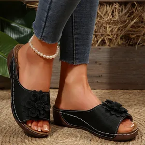 Detalle de sandalias de cuña negras con decoración floral y elegantes costuras blancas