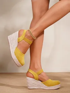 Detalle de sandalias de cuña tipo alpargata amarillas con plataforma de yute trenzado
