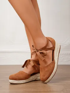 Detalle de espadrilles de ante marrón con suela de plataforma y cintas en el tobillo