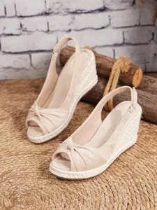 Vista detallada de sandalias de cuña en ante beige con tacón de esparto y punta abierta