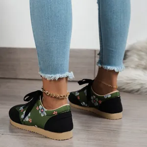 Detailed close-up of green floral print sneakers worn by a model in blue jeans