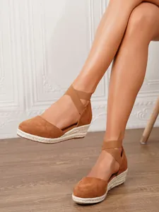 Vista detallada de sandalias de cuña en ante marrón con tiras elásticas en modelo