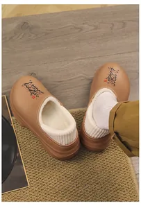 Close-up of camel winter clogs with plush white lining and Lucky graphic detail