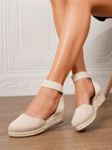 Primer plano de elegantes alpargatas de cuña en lona beige con correa para mujeres.