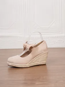 Perfil lateral de alpargatas con cuña de ante beige y detalle de lazo