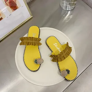 Detailed view of yellow women's flat sandals with ruffles and pineapple pearl decorations