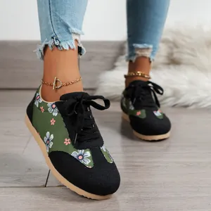 Close-up of floral print canvas sneakers with black laces and tan soles on wooden floor