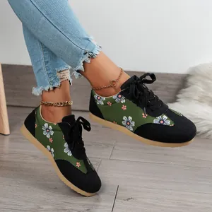 Close-up of women's green floral sneakers with daisy pattern and black laces