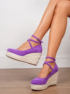 Detalle de las sandalias de cuña en ante morado con plataforma de esparto y tira al tobillo